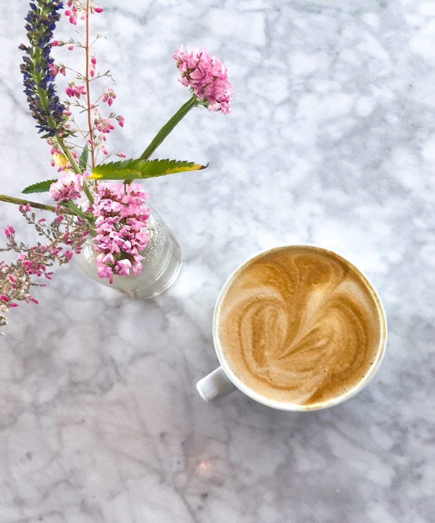 A latte next to a vase of flowers