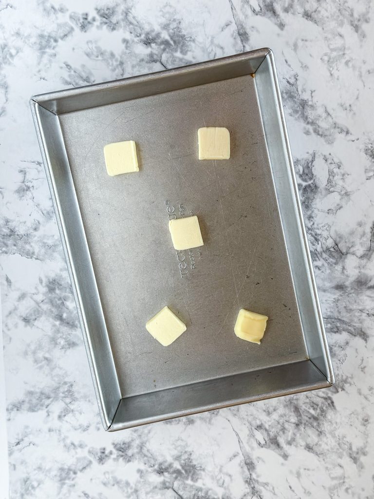 Image of 9x13" Metal baking pan with pats of butter in the bottom of the pan